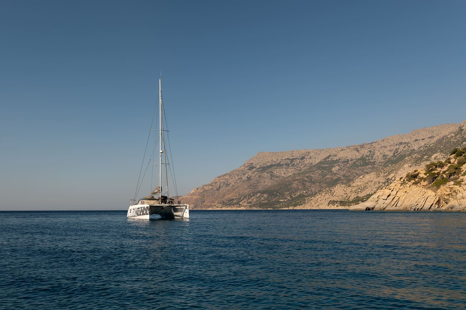 Gajeta — Sailing catamaran anchored off a sandy beach on Ikaria, Greece