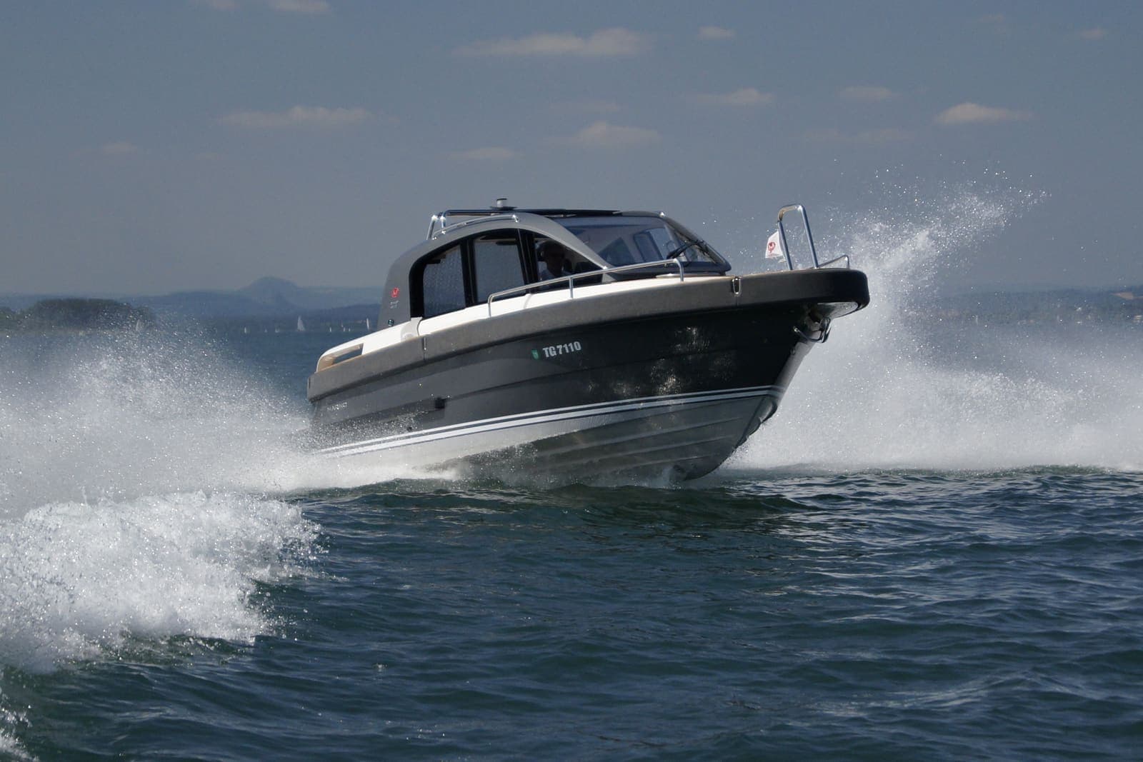 Mare Nostrum — Hardtop motorboat throwing spray as it speeds across the sea